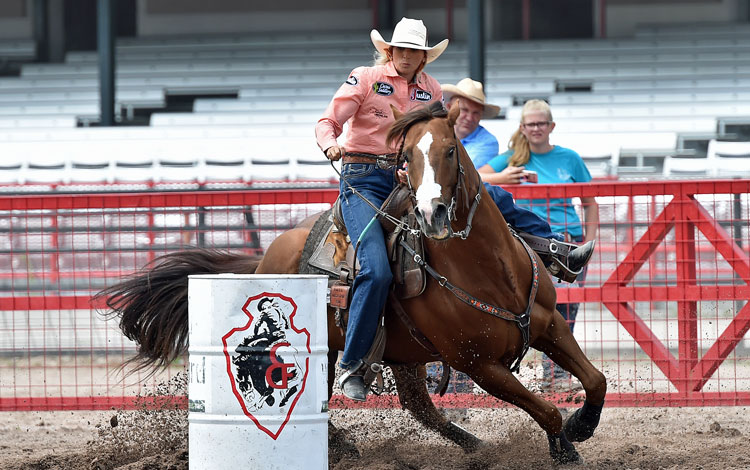 La corredora de barriles Shali Lord y su caballo giran un barril en el Cheyenne Frontier Days Rodeo.